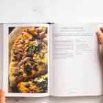 A Woman reading a itallian pizza cook book